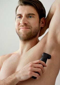 Close up photograph of a man from the back using a Philips body groomer to shave his back