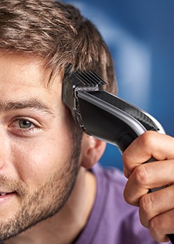 Cropped photograph of a man using Philips clippers to cut his hair
